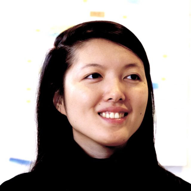 Stacy Hsueh, an Asian woman. She is smiling, looking away from the camera, against a bright background