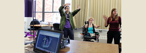AccessEngineering students and CREATE Associate Director Katherine M. Steele work on modeling for accessibility tools. One student is standing, the other is in a power wheelchair.
