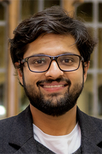 Headshot of Professor Dhruv Jain, wearing dark framed eyeglasses and a suit jacket.