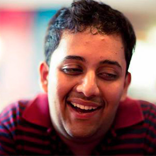 Venkatesh Potluri leans toward the camera smiling with eyes cast downward