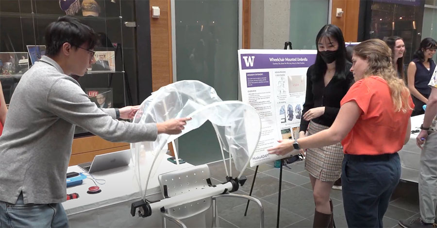 Students presenting the Wheelchair-Mounted Umbrella project demo and poster.