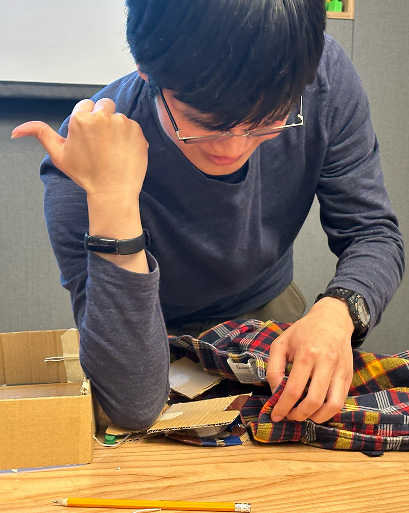 An adaptation hackfest participant demonstrates their team's prototype: A device to assist with pulling up pants for a person who uses prosthetics.