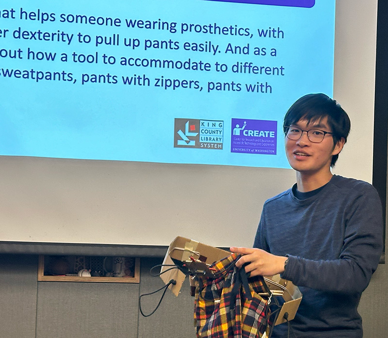 An adaptation hackfest participant presents their team's prototype: A device to assist with pulling up pants for a person who uses prosthetics.