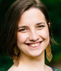 Sasha Portnova, a white woman, with brown hair. She is smiling warmly at the camera.