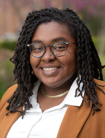 Theadshot of Jazette Johnson wearing a white shirt and amber colored blazer. She is smiling warmly.