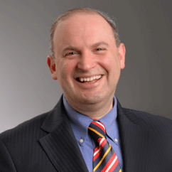 Jonathan Lazar, with a big smile and wearing a suit and multi-colored tie.