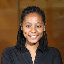 Aaleyah Lewis, a Black woman with black locs pulled back, wearing a black button up shirt, smiling at the camera.
