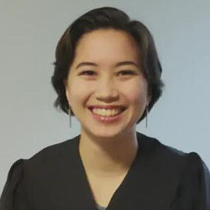 Annika Pfister poses in front of a neutral background. She has short dark hair and smiles broadly.