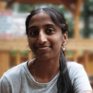 Tanvi Banchu seated at an outdoor cafe gazing warmly toward the camera.
