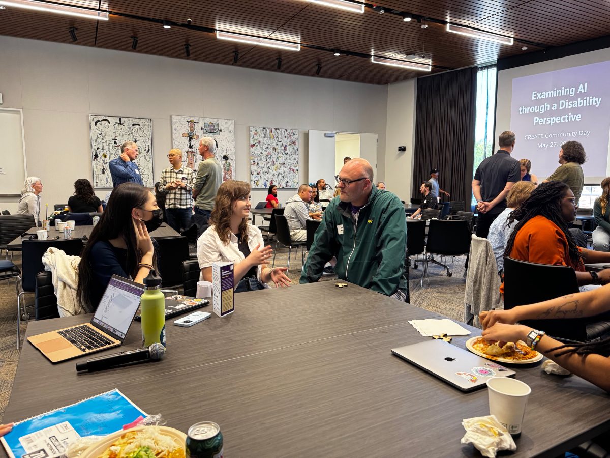 Photo of attendees seated or standing in casual discussion groups.