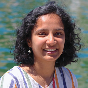 Aashaka Desai, a young woman with wavy brown hair. In the background there's rippled water.