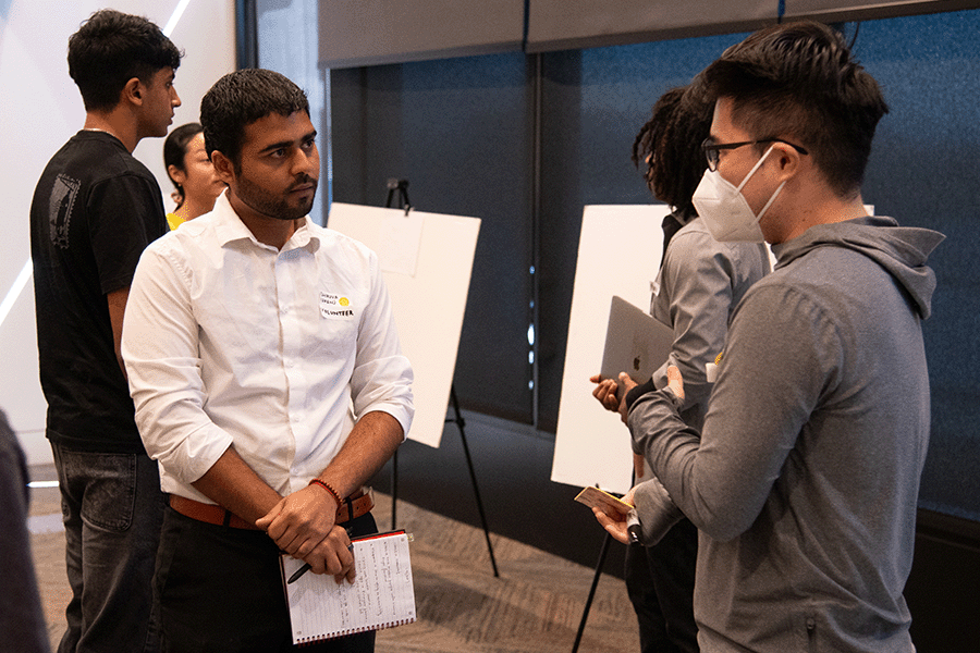 Participants at CREATE Accessibility Hackfest - Summer 2026 deep in discussion and standing around poster boards for recording brainstorming ideas
