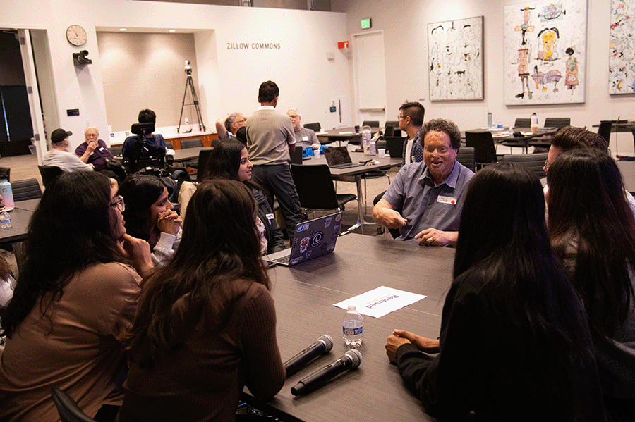Joshua Miele speaks at a table with seven participants at CREATE Accessibility Hackfest - Summer 2026. In the background are two other discussion tables.