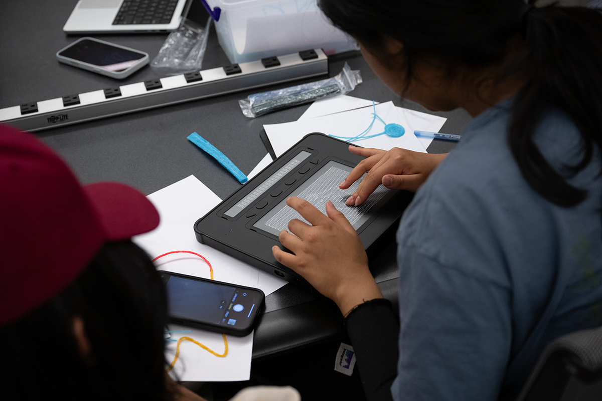 Closeup of an intern's hands as they work on a CADA11y tablet.