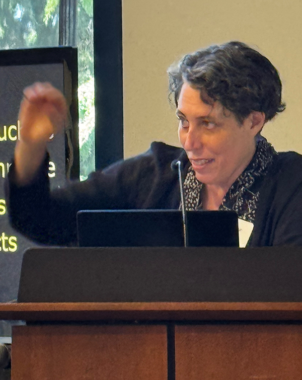 Dr. Jennifer Mankoff gestures with one hand while speaking at a podium.