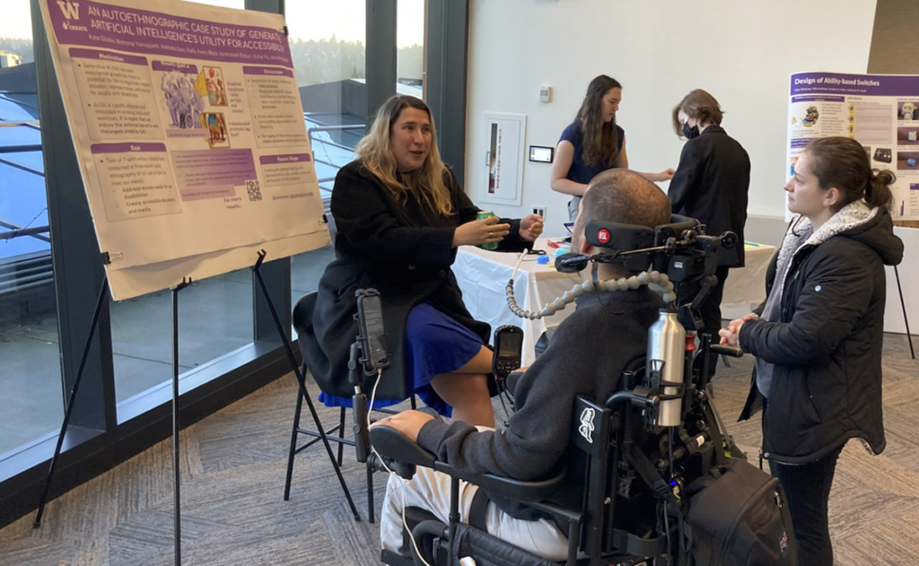 Kenny Salvini, Co-founder and President of The Here and Now Project, is in his power wheelchair, learning about an analysis of accessibility and ableism in current generative AI from Kate Glazko.