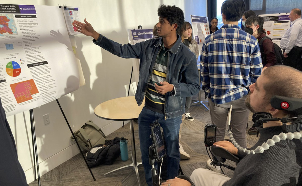 Kenny Salvini, Cofounder and President of CREATE Community Partner The Here and Now Project, listens intently as a student presents a project that analyzes access to public transit by considering factors like median household income.