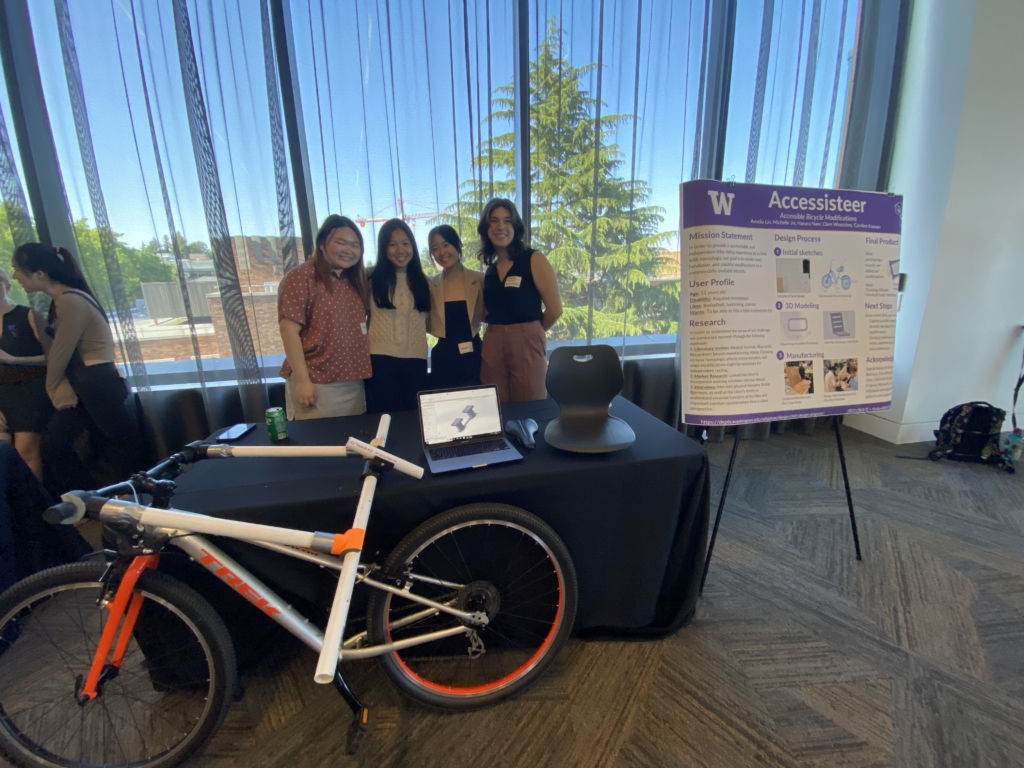 Students stand by their project table with a prototype for an adaptable bicycle.