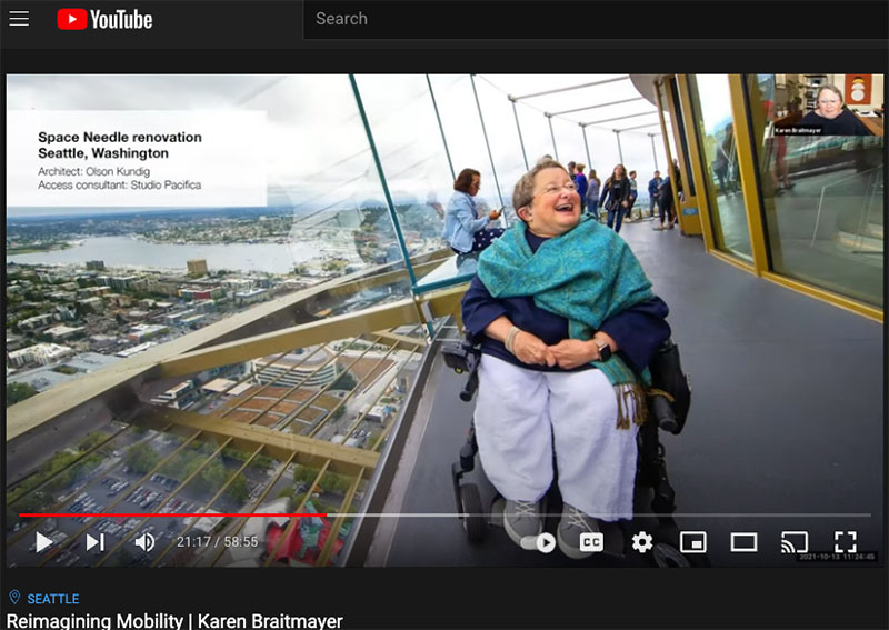 Karen Braitmayer, seated in her wheelchair on the observation deck of the Space Needle, with full view of Seattle because obstructive walls were removed in a remodel