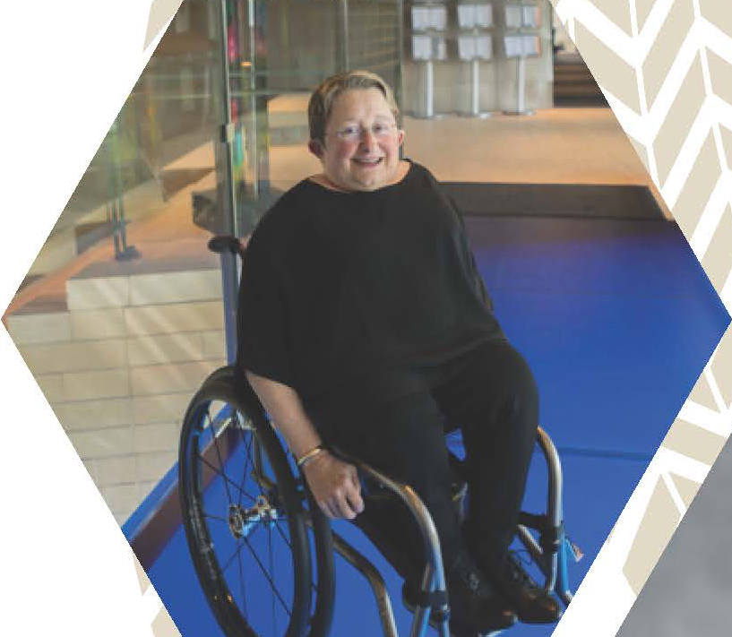 Karen Braitmayer using a wheelchair in a modern building with stairs and ramps