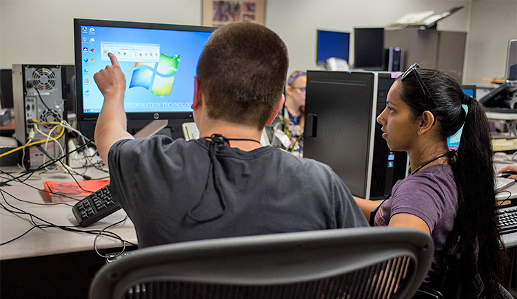 Two students work together in a lab on a computer screen using accessibility tools