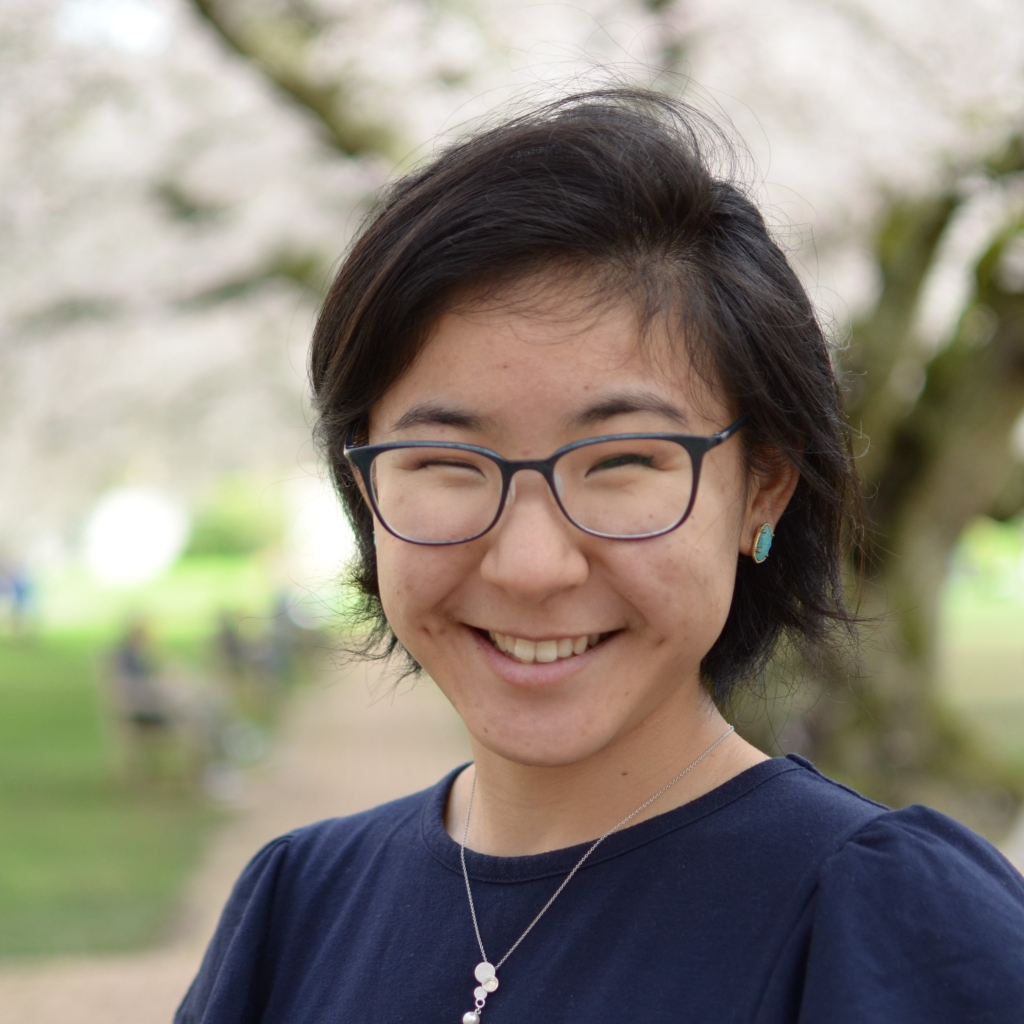 Headshot of Momona Yamagami in front of the UW cherry trees in bloom