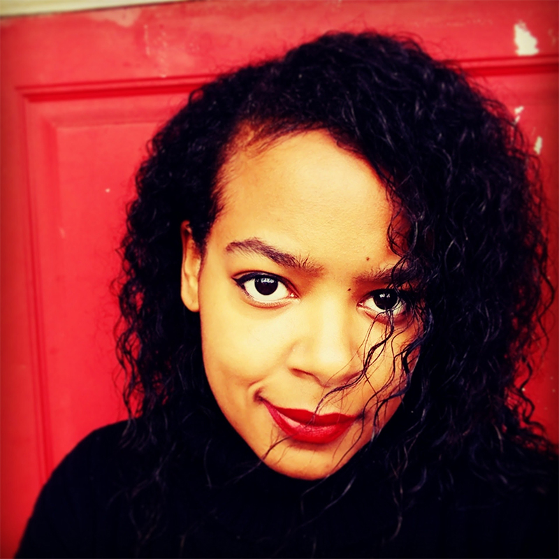 ChrisTiana ObeySumner: a Black, queer, non-binary, and multiply disabled researcher in front of a bright red background