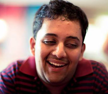 Venkatesh Potluri leans toward the camera smiling with eyes cast downward.